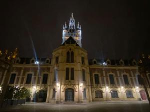 un grand bâtiment avec une tour d'horloge la nuit dans l'établissement Appartement 4 - Hyper centre - 1 à 4 personnes, à Douai