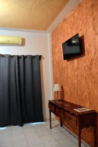 Habitación con escritorio y TV en la pared. en Casa Vieja Hotel y Restaurante en San Lorenzo