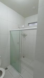 a bathroom with a toilet and a glass shower stall at Mandala Hostel Maragogi Oficial in Maragogi