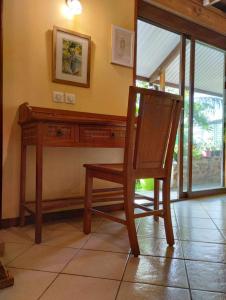 silla de madera en una habitación con escritorio en Tema'e Beach House en Temae