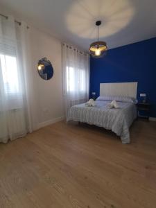 een slaapkamer met een bed met een blauwe muur bij Casa Elisa 3 in León