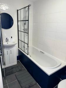 Baño blanco con bañera y lavamanos en Blue Madison en Aldershot