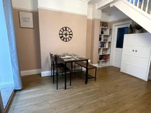 a dining room with a table and chairs and a clock on the wall at Comfy home in Newport in Newport