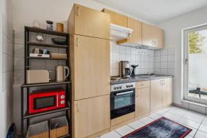 a kitchen with wooden cabinets and a red microwave at Comfort Apartment - bis 4 Pers - Neunkirchen City - Parkplatz - Garage - WiFi - Bad - Balkon in Neunkirchen