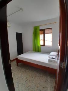 een slaapkamer met een bed en een groen raam bij Hotel Bruselas Mutata in Mutatá