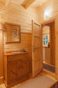 a wooden bathroom with a sink and a door at Family friendly sunny Log Cabin in Wimborne Minster