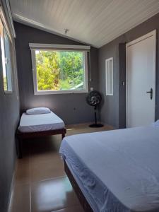 a bedroom with a bed and a window and a fan at Espaço Verano- quarto Família in Niterói