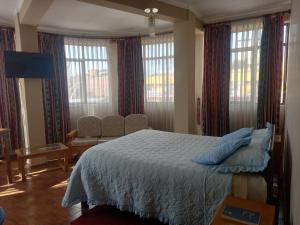 a bedroom with a bed and a chair and windows at HOTEL NOBLEZA in Potosí