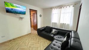 ein Wohnzimmer mit einem schwarzen Sofa und einem Flachbild-TV in der Unterkunft Acogedor apartamento esquinero, a una cuadra del parque principal in Líbano