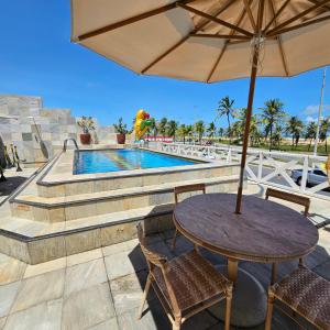 una mesa con sombrilla junto a la piscina en Jatobá Praia Hotel, en Aracaju