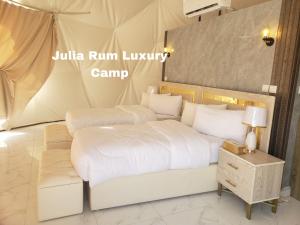 a bed with white sheets and pillows in a room at Julia Rum Luxury Camp in Wadi Rum
