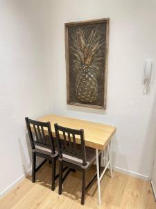a table with two chairs and a painting of a pineapple at Moderne Wohnung in Unna Mitte in Unna