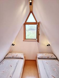 two beds in a attic room with a window at Nurdachhaus am Geyersberg in Freyung