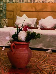 un vase rouge avec des fleurs sur une table dans l'établissement Dar Merzouga Meknes, à Meknès