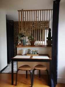 a kitchen with a table and two stools and a sink at Au Gray du temps suspendu in Pleslin-Trigavou