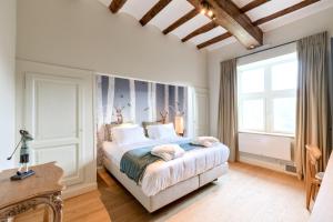- une chambre avec un grand lit et une grande fenêtre dans l'établissement Le Gîte du Domaine des Trois Tilleuls, à Villers-la-Ville