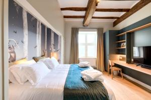 a bedroom with a large bed and a flat screen tv at Le Gîte du Domaine des Trois Tilleuls in Villers-la-Ville