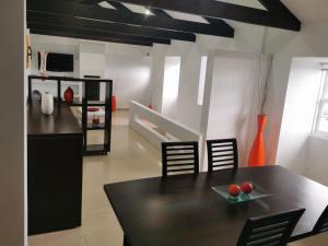 a kitchen with a black table and chairs in a room at Alojamento M.A. in São Roque do Pico