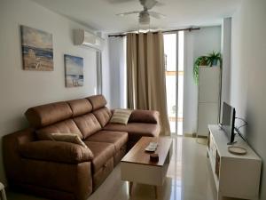 a living room with a brown couch and a tv at Apartamento Isla San Andrés in Carboneras
