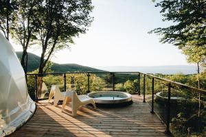 a deck with a hot tub and two chairs at Dômes Charlevoix in Petite-Rivière-Saint-François