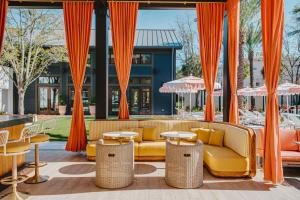 a patio with orange curtains and couches and tables at Hotel Bardo Savannah in Savannah