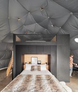 1 dormitorio con 1 cama grande y techo gris en Dômes Charlevoix, en Petite-Rivière-Saint-François