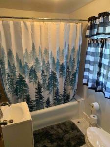 uma casa de banho com uma cortina de chuveiro com árvores em Lasalle Getaway Home! em Niagara Falls