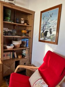 un soggiorno con una sedia rossa e una libreria di Nel cuore dell’Oasi Zegna a Bielmonte
