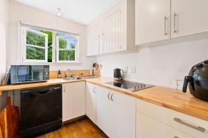 a kitchen with white cabinets and a black dishwasher at Bach Haven - Mangakino Holiday Home in Mangakino