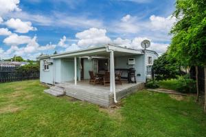 a small blue house with a deck with a table at Bach Haven - Mangakino Holiday Home in Mangakino