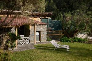 un patio con una silla blanca en el césped en Casas Maravilha by Madeira Sun Travel, en Calheta