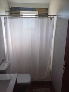 a bathroom with a white shower curtain and a toilet at La Demorada, cómoda casa en entorno natural in Mercedes +9 photos