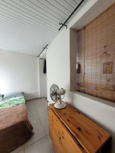 1 dormitorio con 1 cama y una mesa de madera con ventilador. en Tropical urban en Schœlcher