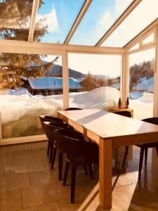 einen Holztisch und Stühle in einem Zimmer mit Fenster in der Unterkunft The Holiday Home Davos in Davos