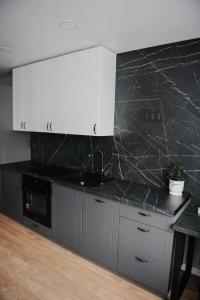 a kitchen with a black counter top and white cabinets at JAUKI STUDIJA KRETINGOS CENTRE in Kretinga