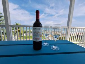 a bottle of wine sitting on a table with two glasses at Paunch Beach Retreat in Bocas del Toro