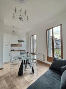 a living room with a table and chairs and a kitchen at Appartement de charme avec balcon au pied des commerces in Béziers