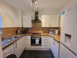 a kitchen with white cabinets and a sink and a microwave at Free Parking: Perfect City Centre Flat in Manchester