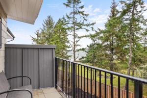 a balcony with a black railing and trees at Seas The Day Saratoga at THE BEACH HOUSE in Campbell River