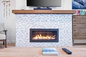 sala de estar con chimenea y TV en Seas The Day Saratoga at THE BEACH HOUSE, en Campbell River