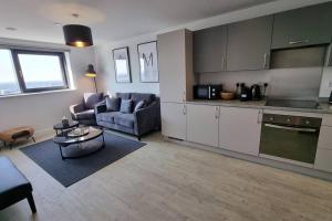 uma cozinha e sala de estar com um sofá e uma mesa em 2 Bedroom Penthouse em Manchester