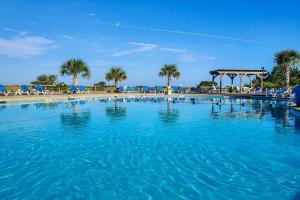 una gran piscina con palmeras y cenador en Saint Helena Island Condo - Steps to Beach!, en Oceanmarsh Subdivision