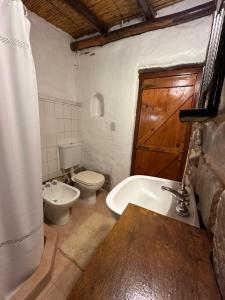 a bathroom with a toilet and a tub and a sink at La Hoyada in Tilcara