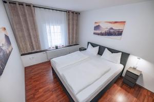 Un dormitorio con una gran cama blanca y una ventana en Gästehaus Remo, en Hermagor