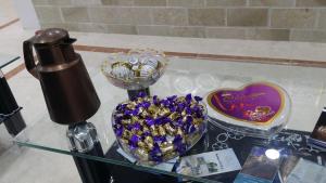 a glass table with a heart shaped bowl of purple flowers at Al Afiah Corniche Hotel Apartment in Sur