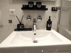 a white sink in a bathroom with black items on it at *Vivere Apartment 13 Stock, Ausicht, Zentrum, NEU in Augsburg