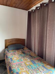 1 dormitorio con 1 cama con edredón y cortinas en Hospedaje La Blanquita, en Santa Juana
