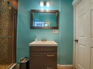 baño con lavabo y espejo en una pared azul en Modern Getaway, Single Bedroom Full Apartment en Niagara Falls