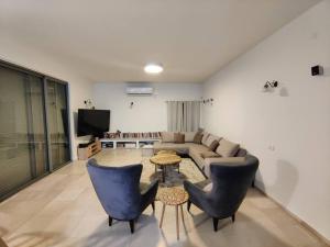een woonkamer met een bank en 2 stoelen bij וילה בגלבוע in Kfar Yehezkel