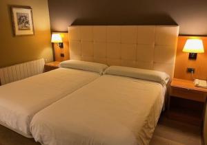 - un grand lit blanc dans une chambre d'hôtel dans l'établissement Coto Real, à Rábade